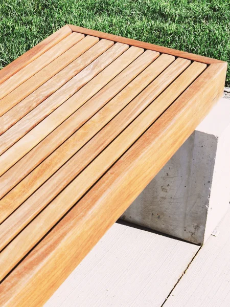 Banc en bois verni posé sur 2 plots en pierre en extérieur